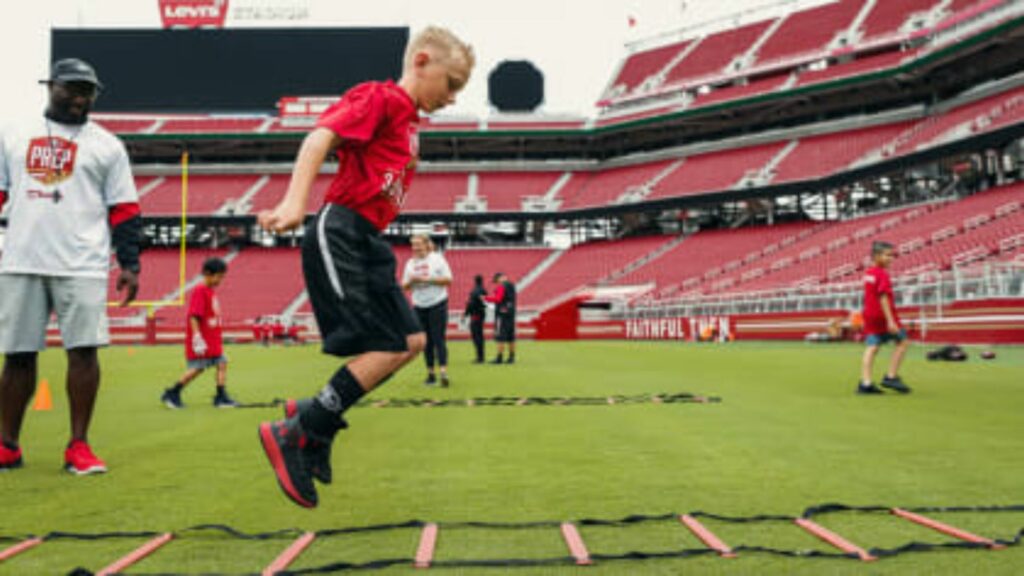 a boy doing football footwork with his coach looking 